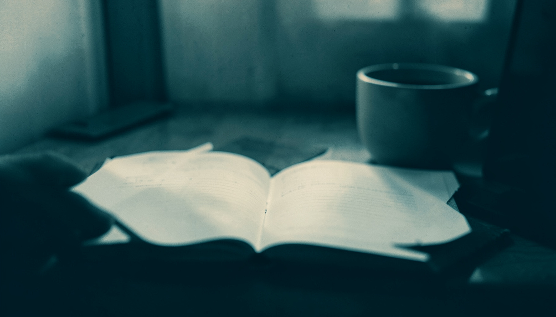 A muted two-tone duotone photograph of a quiet desk scene with an open notebook and a cup, rendered in deep teal shadows and pale warm highlights, evoking a thoughtful, inquisitive mood
